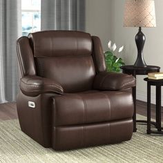 a brown recliner chair sitting in a living room next to a table and lamp