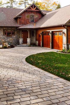 a large brick driveway leading to a house with two garage doors on the front and side