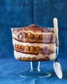 an ice cream sundae with chocolate and bananas in it on a glass stand next to a blue background