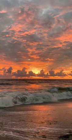 the sun is setting over the ocean with clouds in the sky and waves on the beach