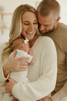 a man and woman holding a baby in their arms