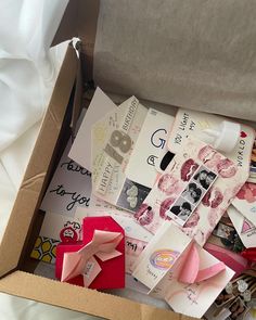 a box filled with lots of different types of papers and decorations on top of a bed