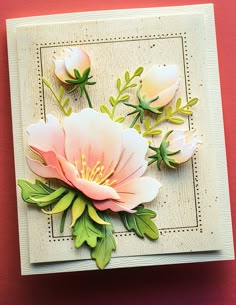 a close up of a card with flowers and leaves on the front, sitting on a red surface