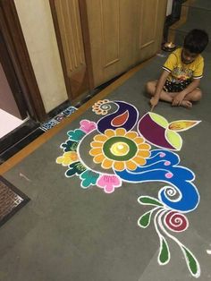 a little boy sitting on the floor drawing with chalk