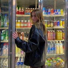 a woman standing in front of a refrigerator filled with drinks