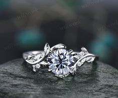 a white gold engagement ring with leaves on the band and a round diamond center stone