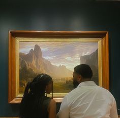 a man and woman looking at a painting