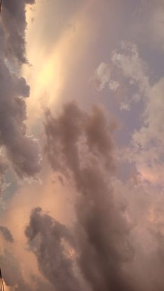 the sky is filled with clouds and some kites are flying in the air at sunset