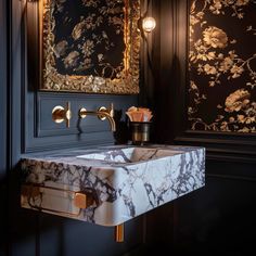 a bathroom sink with a marble counter top and gold faucet fixtures in the corner