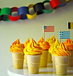 cupcakes with orange frosting and flags are on a white cake platter