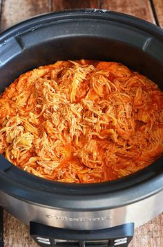 shredded carrots in a slow cooker on a wooden table