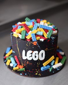 a lego themed cake with sprinkles and letters on the top, sitting on a table