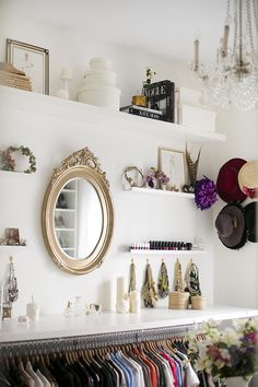 a room filled with lots of different colored shirts and hats on shelves next to a mirror