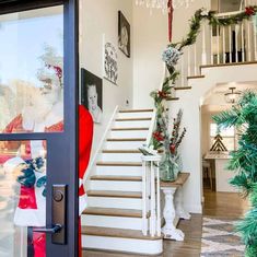 christmas decorations are on display in the entryway to a house with stairs and wreaths