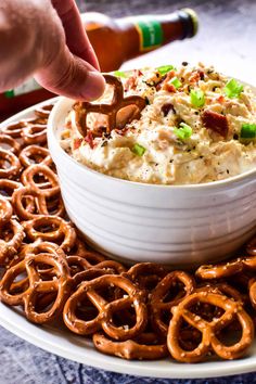 a bowl of dip surrounded by pretzels and pretzels on a plate