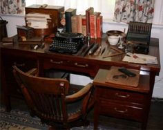 a desk with an old fashioned typewriter and many books