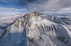 an aerial view of the top of a mountain with clouds in the sky above it