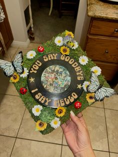 someone is holding up a graduation cap decorated with flowers and butterflies that says you say goodbye