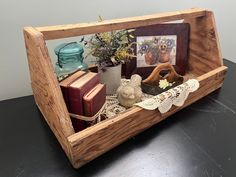 a wooden frame with pictures and flowers in it sitting on a table next to books