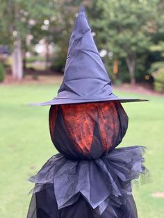 a close up of a person wearing a witches hat on top of a grass field