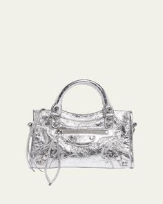 "Find BALENCIAGA Le City Mini Top Handle Bag on Editorialist. The Balenciaga Le City Mini top handle bag is crafted from metallic lamb leather and features rolled top handles, a detachable, adjustable shoulder/crossbody strap, and a zip top closure. It also includes an exterior front zip pocket and an interior zip pocket. The bag can be worn as a top handle or shoulder/crossbody bag. The bag measures approximately 6.3\"H x 9.4\"W x 2.5\"D. Wipe clean. Made in Italy." Mini Top Handle Bag, Leather Roll, Mini Top, Handle Bag, Metallic Leather, Zip Top, Crossbody Strap, Leather Top, Sale Design