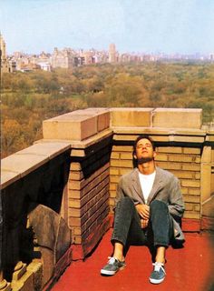 a man sitting on top of a building next to a red floor covered in cement