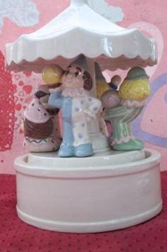 a small figurine is standing under a white umbrella on a red tablecloth