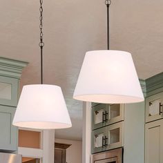 two lamps hanging from the ceiling in a kitchen