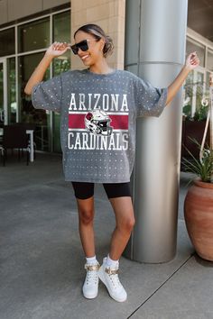 Make a statement in any crowd with our Arizona Cardinals oversized fit, all-over mini rhinestone short sleeve tee featuring a ribbed neckline. Embrace the sparkle while staying comfortable—perfect for every dedicated fan. Gray Graphic Print Top For Game Day, Gray Fan Apparel Top For Game Day, Gray Fan Apparel Tops For Game Day, Game Day Tops With Sublimation Print Short Sleeve, Gray Short Sleeve Fan Apparel Top, Sublimation Print Short Sleeve Tops For Game Day, Short Sleeve T-shirt For Summer Cheerleading, Summer Short Sleeve T-shirt For Cheerleading, Summer Crew Neck T-shirt For Cheerleading