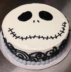 a decorated cake with white frosting and black icing on it's face