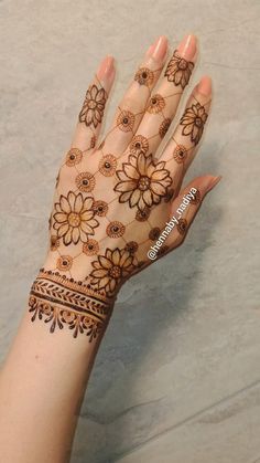 a woman's hand with henna on it and flowers painted on the palm