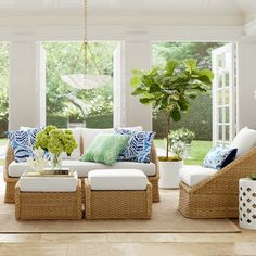 a living room with wicker furniture and green plants in the window sills