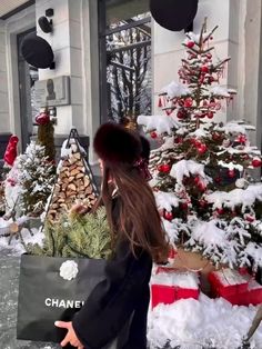 a woman holding a chanel bag in front of a christmas tree