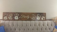 a wooden sign that says family with handprints on it and two blue pillows