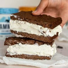 a person is holding two ice cream sandwiches in front of the camera, and they are stacked on top of each other