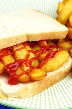 a sandwich with ketchup and french fries on a blue and white plate,