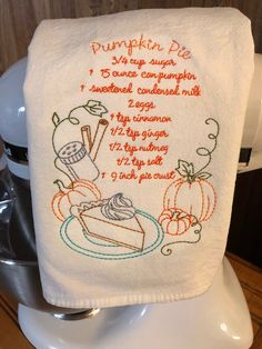 a white towel with an embroidered recipe for pumpkin pie on it sitting on top of a toilet