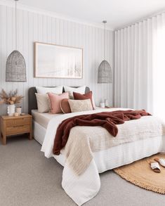 a bedroom with white walls and carpeted flooring has a large bed covered in blankets