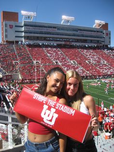 two women pose for a photo at a stadium