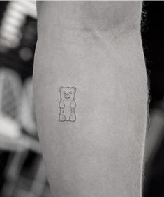 a small teddy bear tattoo on the right arm and leg, with an outline of a teddy bear