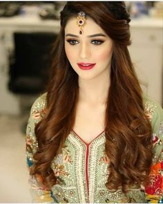 a woman with long brown hair wearing a headpiece and makeup looks at the camera