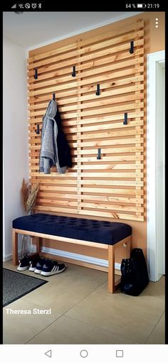 a wooden bench sitting in front of a wall with shoes on the floor and coat rack