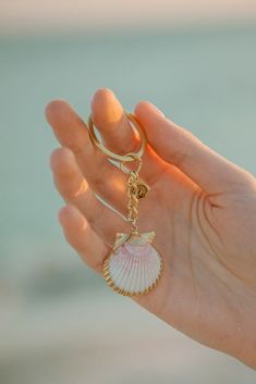 a hand holding a shell shaped keychain with a ring on it's thumb