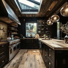 a kitchen with wooden floors and black cabinets, skylights above the stove top oven