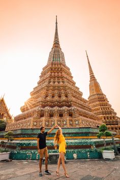 a man and woman standing in front of a large building with many spires on it