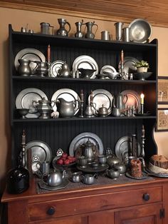 a china cabinet filled with lots of silverware on top of wooden shelves next to a wall