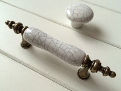 two white door knobs with cracky paint on them and one has a metal handle