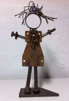 a metal figure with two wrenches on it's head and arms, standing in front of a white wall