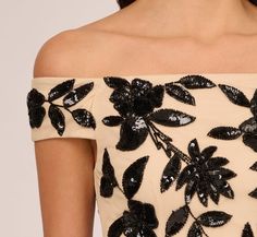 a woman wearing a black and white dress with flowers on the shoulder, close up