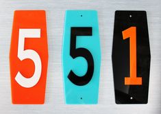 three numbered numbers are displayed on a white surface with orange and blue trimmings